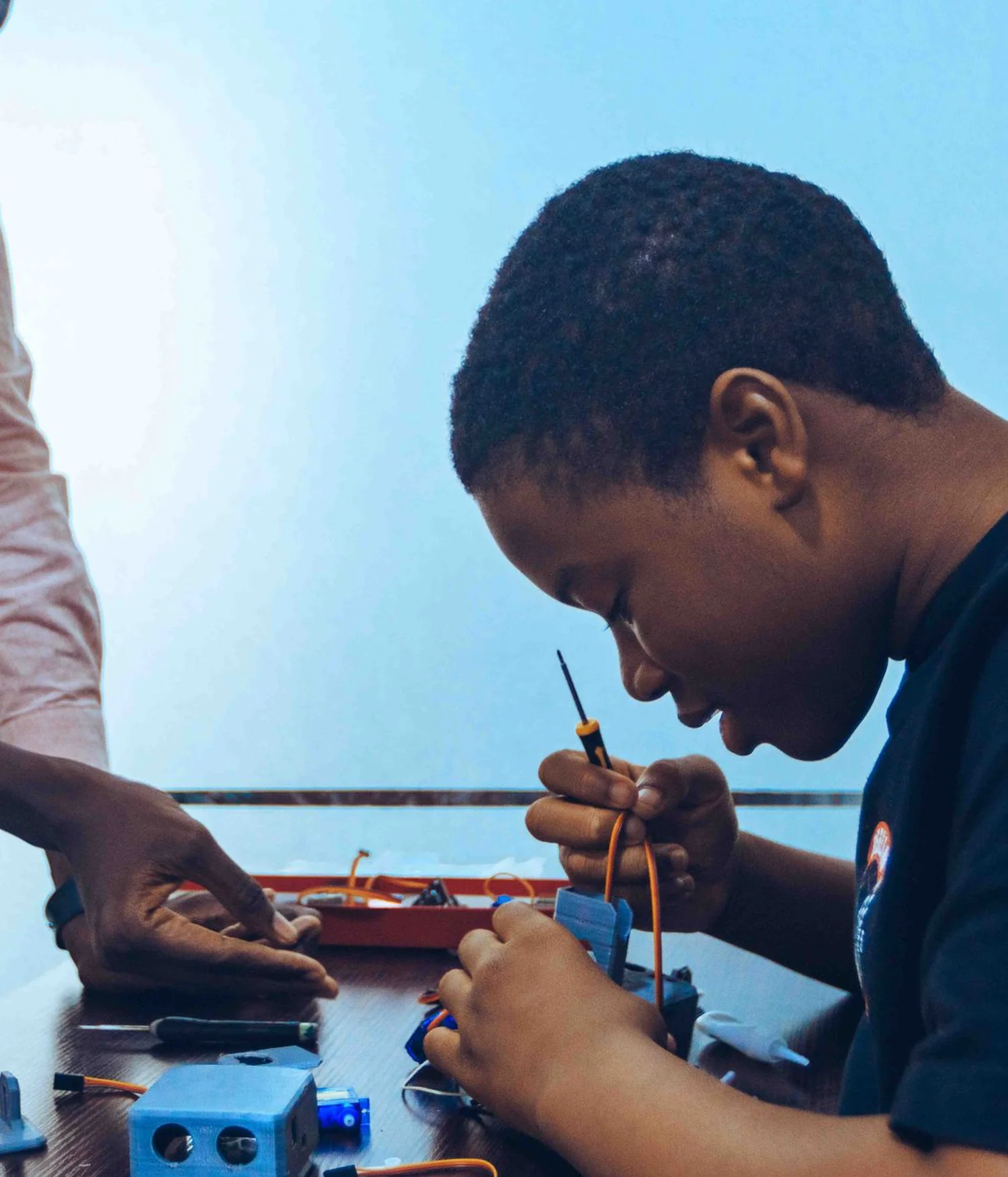 Estudiante concentrado construyendo un prototipo electrónico con acompañamiento
